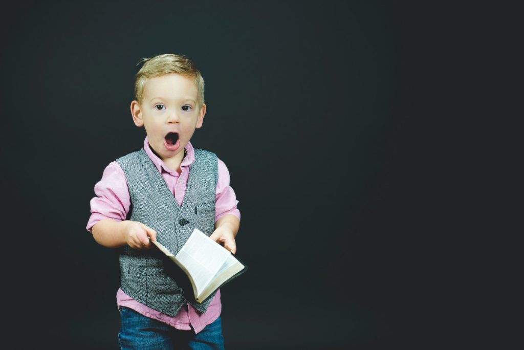 Little boy with book in hand is totally amazed